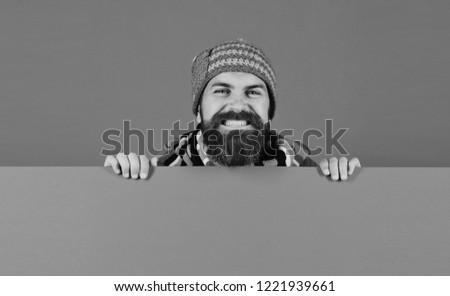 Autumn and demi season clothes concept. Hipster with beard and wide smile wears warm clothes. Man in warm hat on green background, copy space. October and November sale idea