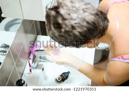 Hair coloring in the bathroom process. Closeup picture on hair coloring process, light background, abstract.  Brush is applying hair color. Shocking facts about hair dye.