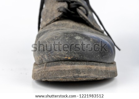 Old black dirty shoes. Leather military footwear on a white table. Light background.