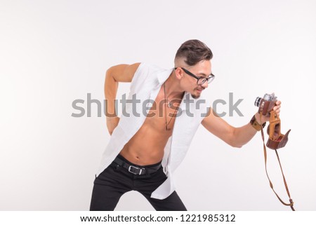 People, photo and style concept - happy young man taking selfie with old photo camera on white background