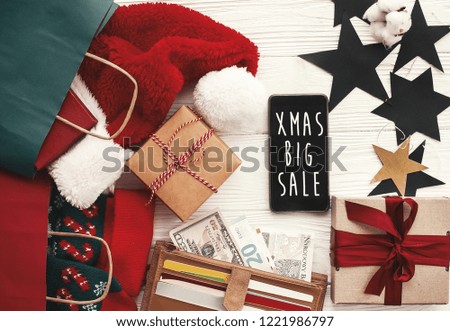Christmas big sale text on phone screen. Special discount christmas offer. Phone with advertising message at money, wallet, bags, clothes, gift boxes, price tags. Shopping time