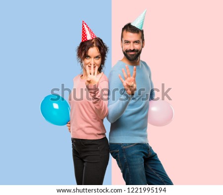 couple with balloons and birthday hats happy and counting four with fingers on pink and blue background