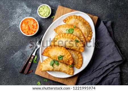 Latin American fried empanadas with tomato and avocado sauces. Top view. Royalty-Free Stock Photo #1221995974
