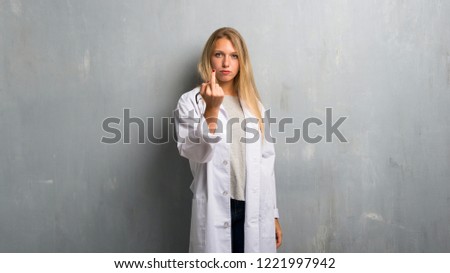 Young doctor woman making horn gesture. Negative expression