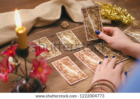 Tarot cards and hands of fortune teller on wooden table background. Royalty-Free Stock Photo #1222004773