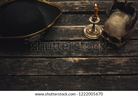 Pirate captain table with pirate hat, human skull and burning candle. Treasure hunter concept background.