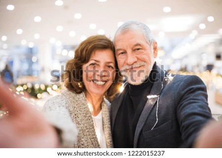 Senior couple taking selfie in shopping center at Christmas time.