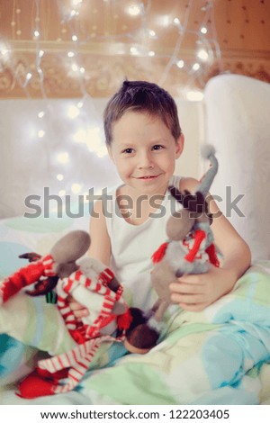 the boy woke up and sat on the bed with toy reindeer