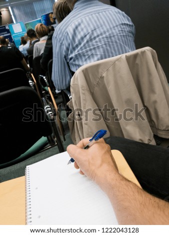 Taking notes at a conference with blue pen.