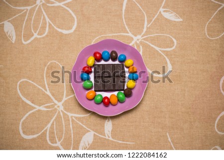 Colorful chocolate candyes lying on the table in the saucer or plate