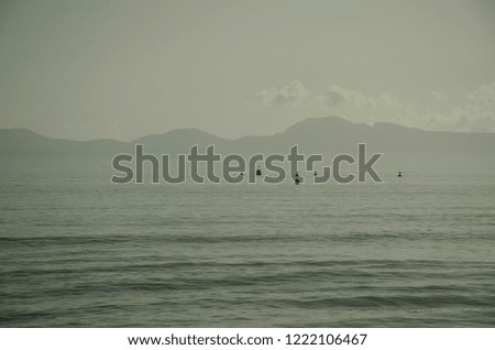Plain landscape with mountains and sea. Calm sea and buoys on it.