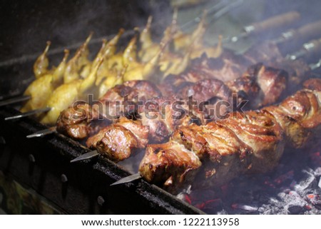 Pork and quail barbecue on skewers frying on a grill brazier 