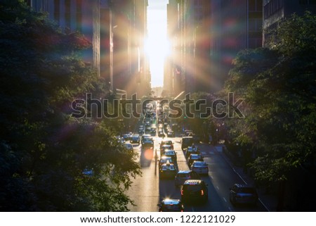 Rays of sunlight shine on the cars and buildings along 42nd Street in Midtown New York City