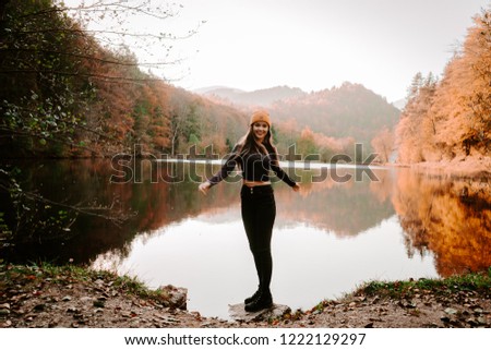 Outdoor autumn portrait of beautiful girl /model /fashion blogger/travel blogger smiling with long hair wearing hat and stylish clothes surrounded by yellow and orange leaves. 