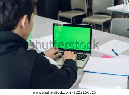 young Asian man working at office space with a laptop.