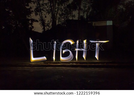 Light - hand writing with flashlight on backyard garden. Light painting - Long exposure photography.