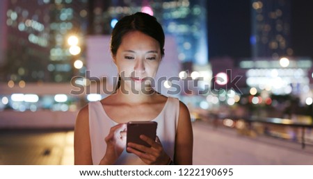 Young Woman send sms on cellphone in city at night