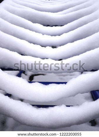 Photo of a blue metal climbing frame with parallel bars covered with a layer of white snow. 