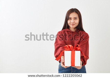 Young Asian woman show OK with a gift box on bright gray wall background