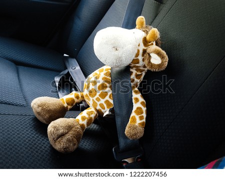 Giraffe doll sitting in the car.