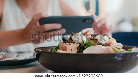Woman take photo on her salad in restaurant