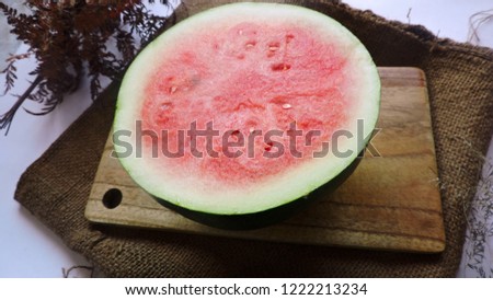 watermelon half slice in a wooden chopping board and background rustic burlap