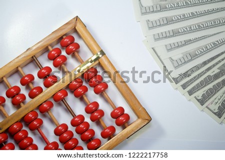 A flatlay picture of abacus or chinese calculator with fake dollar.