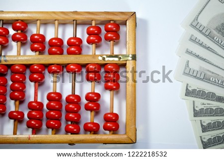 A flatlay picture of abacus or chinese calculator with fake dollar note.