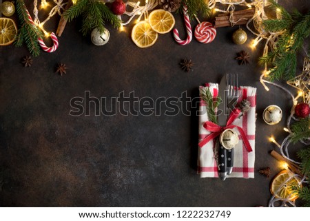 Christmas table setting and border with lights, golden balls, fir branches on dark background with copy space.