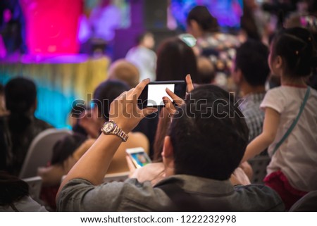 Man takes a picture or shooting video with smartphone during a concert