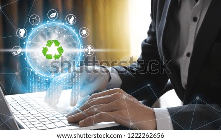 Hand use laptop computer with environment Icons over the Network connection on nature background, Technology ecology concept.