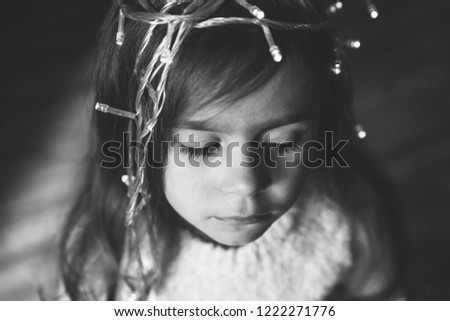Cute little girl with wreath on her head praying at Christmas with closed eyes. Black and white picture. Holy and calm child prayind at Eve.