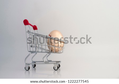 A Golden egg made of metal in a supermarket grocery cart on a gradient light gray background. The concept of a unique offer for the client. Copy space.
