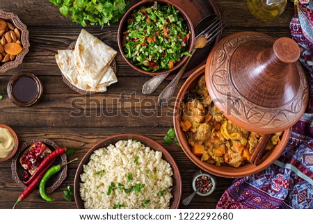 Traditional tajine dishes, couscous  and fresh salad  on rustic wooden table. Tagine lamb meat and pumpkin. Top view. Flat lay Royalty-Free Stock Photo #1222292680
