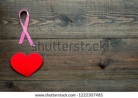 Breast cancer. Mammalogy concept. Symbolic pink ribbon near heart sign on dark wooden background top view copy space
