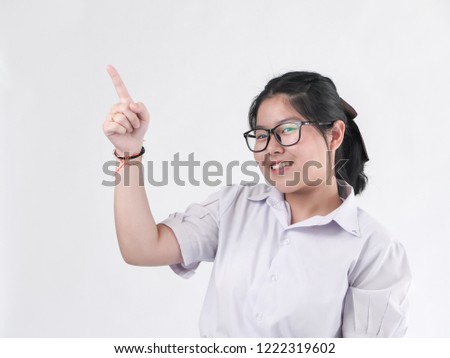 Happy Asian student in uniform pointing something on white background.