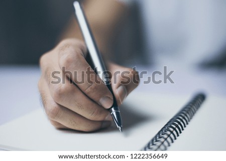 Man is writing on the blank notebook.