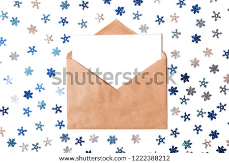 White card and blue and silver streamers and sparkles snowflakes with kraft brown paper envelope Christmas template mock up. Top view, copy space for your text