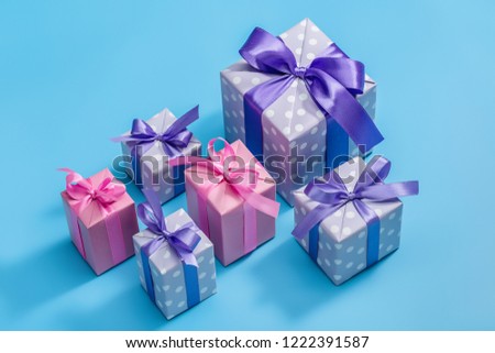 Set of boxes in elegant paper, decorated with ribbons and bows on festive, blue background. View from above. Copy space.