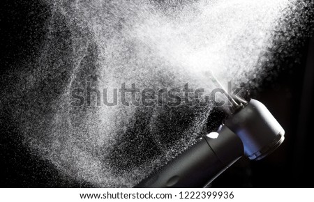 Dental handpiece with diamond bur and water splash motion on dark background. Royalty-Free Stock Photo #1222399936