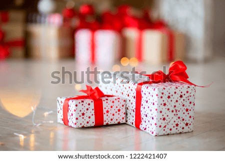 The gift in red packing lies on a floor against the background of other gifts, bokeh