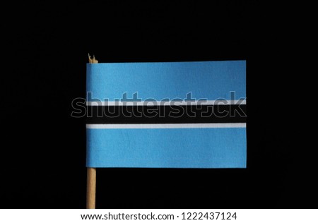 A original and official flag of Botswana on toothpick on black background. Flag consists from light blue field cut horizontally in the centre by a black stripe with a thin white frame.