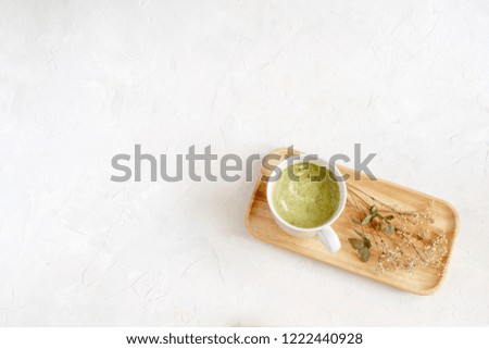 Healthy coffee alternative - matcha latte in white cup on wooden tray, top view, copy space, white background, minimal picture.