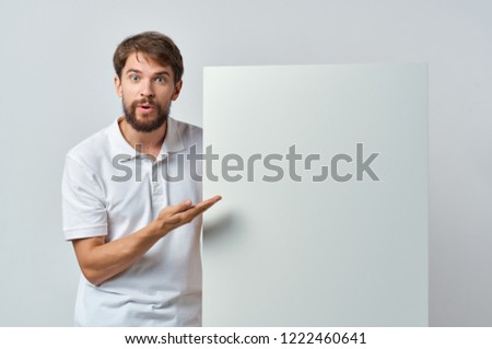 man holds in his hand a white sheet of paper poster mockup                             