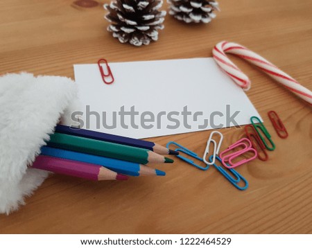 Stocking With Colored Pencils, Blank Paper, Pine Cones And Paper Clips Laying On A Wooden Background