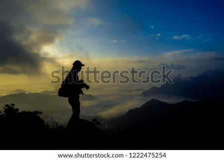 Silhouette of a young  like to travel and photographer, taking pictures of the beautiful moments during the sunset ,