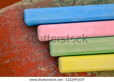 Colored chalk sticks on old wood board as copy space background. Education or back to school concept