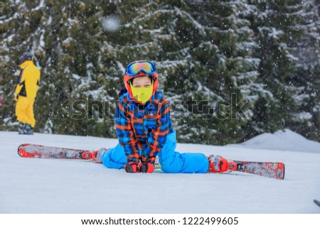 Cute happy skier boy in a winter ski resort.