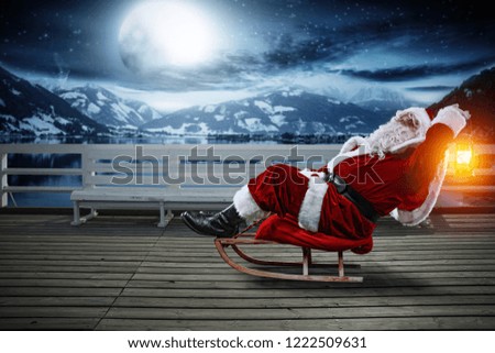Santa Claus and wintr night. Wooden pier with bench and landscape of mountains and lake. Moon light and free space for your decoration. 