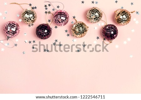 Border of Christmas decorations and copy space on a pink  background. Composition of mirror ballss and sparkles stars. Top view, flat lay.
